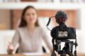 A woman is sitting at a table with a video camera and the best microphone for Sony A7iii in front of her.