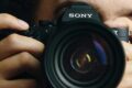 A person holding a Sony camera near his eyes.