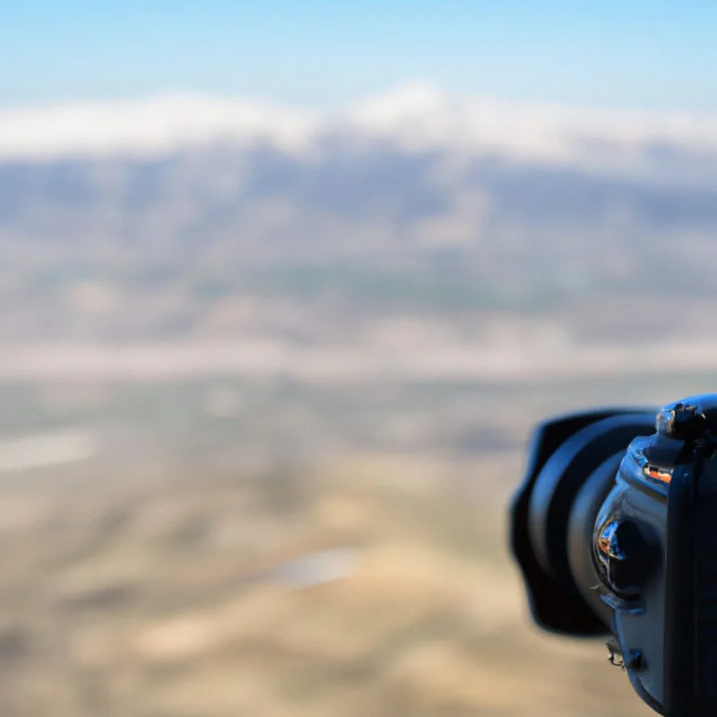 An image of a camera overlooking a vast mountain range, with a clear focus on the foreground and background, illustrating the concept of a deep depth of field