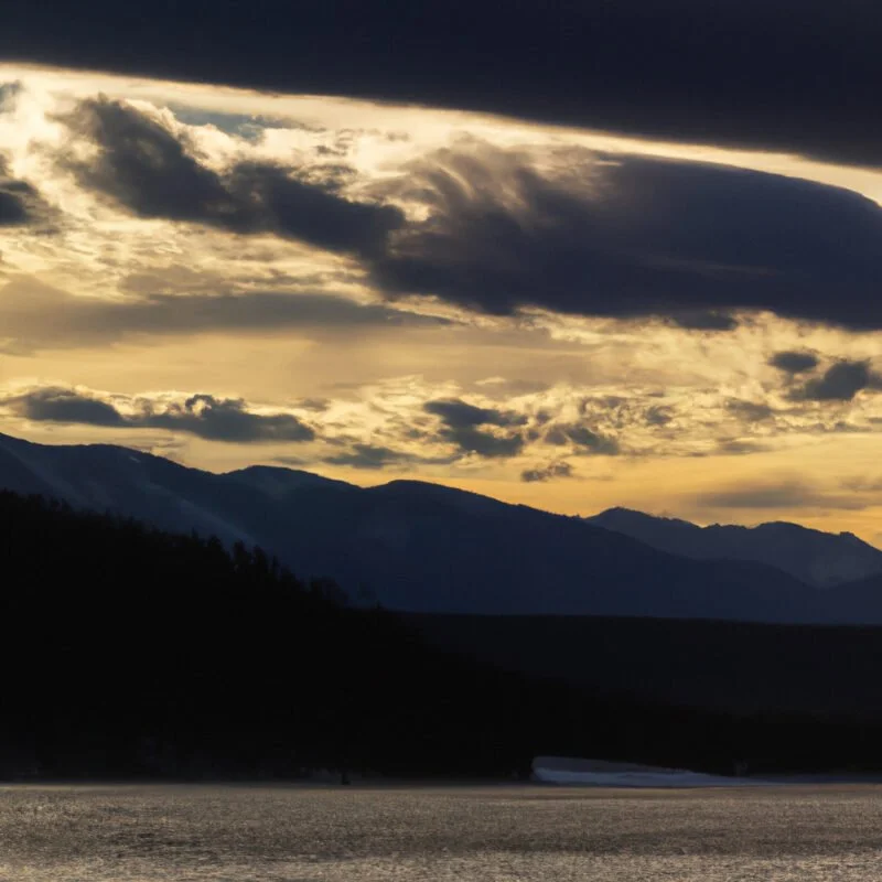 An image showcasing various cloud types filtering sunlight over a diverse landscape, highlighting the soft, diffused lighting effects on mountains, forests, and a serene lake